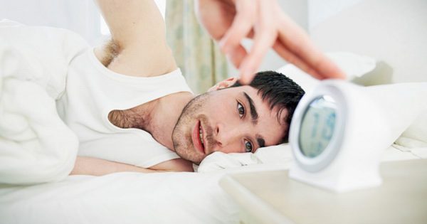 man-in-bed-turning-off-alarm-clock